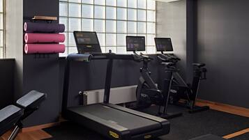 A gym with treadmills, elliptical machines, and a bench.