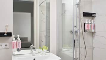 Un baño moderno con ducha de vidrio, un lavabo blanco y un espejo encima.