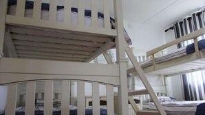 A bunk bed room with a ladder, a window with curtains, and a bed with striped bedding. - Campismo Ninho 28 (Ponta d'Ouro)