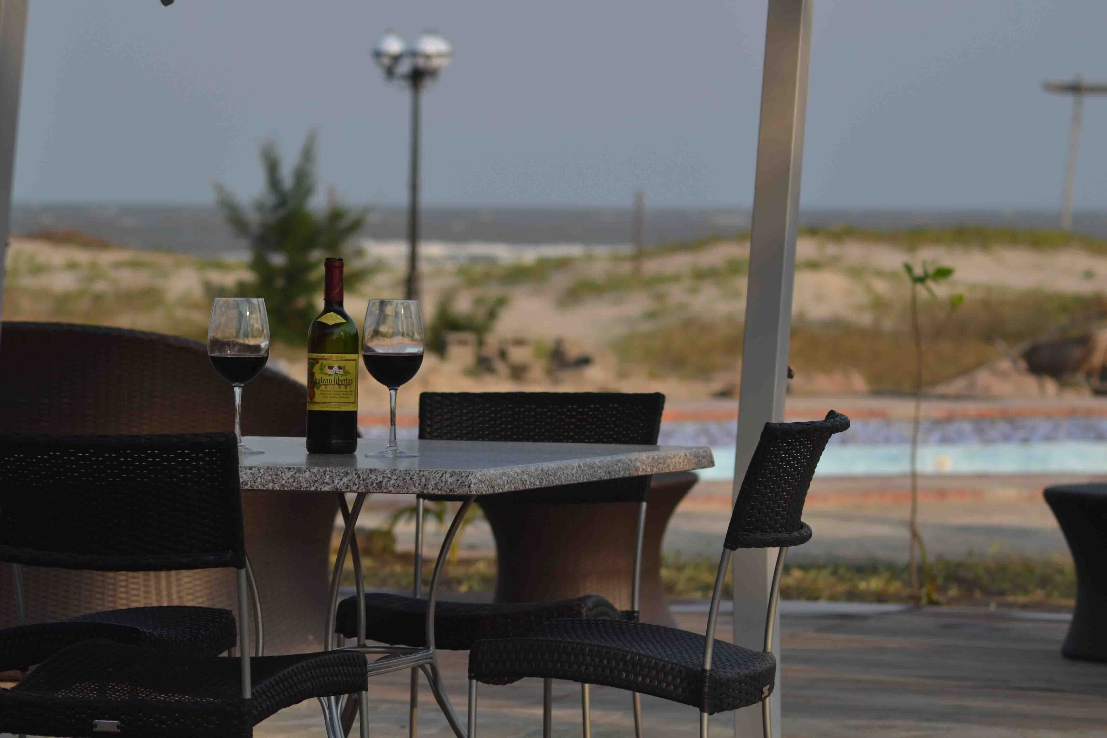 An outdoor seating area with a table and chairs, a bottle of wine, and a glass of wine.