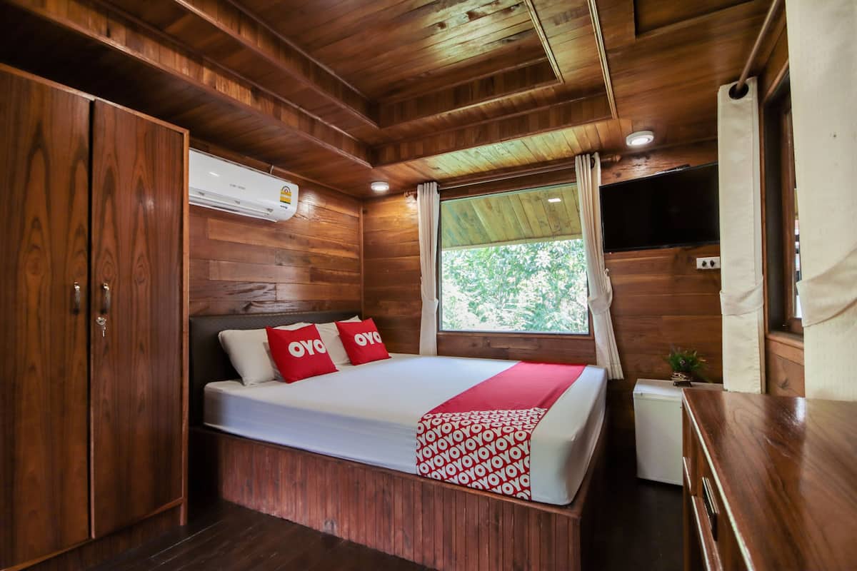 A wooden cabin room with a bed, a small desk, and a television.