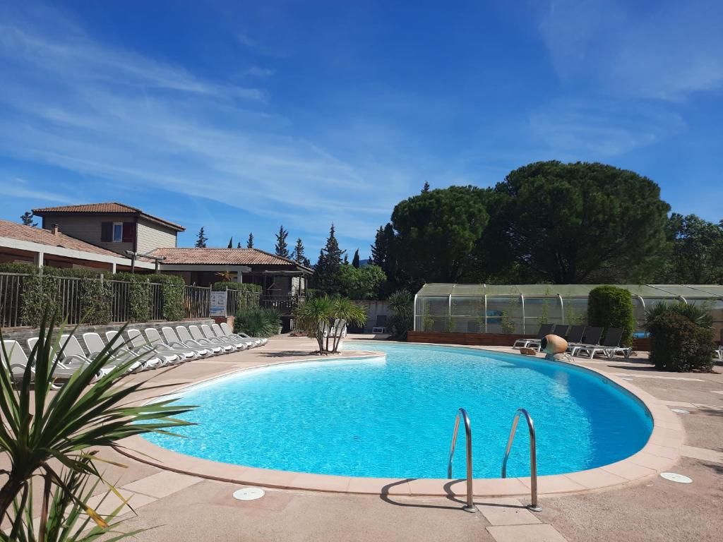 Une piscine à l’eau d’un bleu cristallin, entourée de chaises longues et d’une structure en forme de serre.