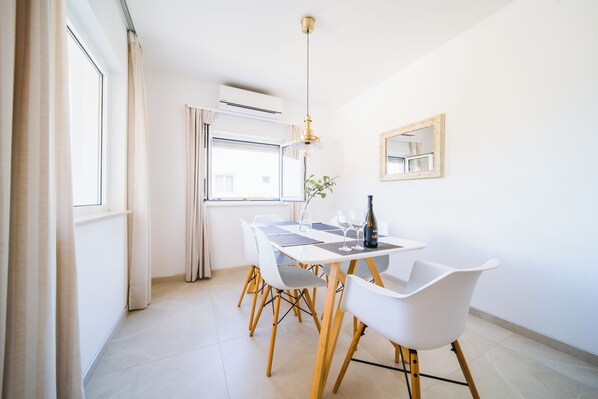 A modern dining area with a white table, wooden chairs, and a hanging light fixture. - Villa Teuta (Korcula)