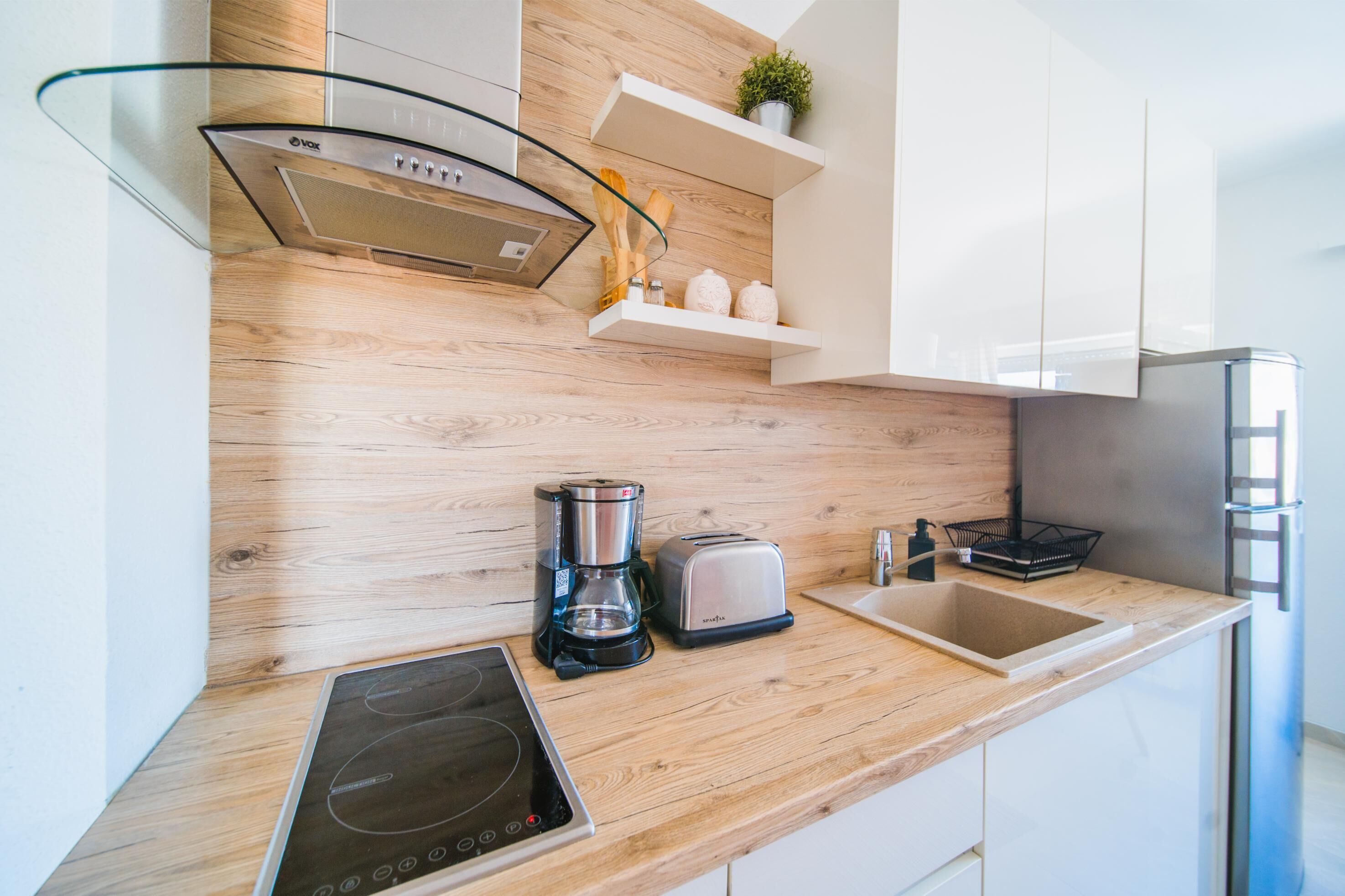 A modern kitchen with a wooden countertop, a built-in stove, a coffee maker, a toaster, and a sink.