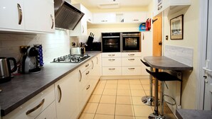 Una cocina moderna con armarios blancos, electrodomésticos de acero inoxidable y piso de baldosas.
