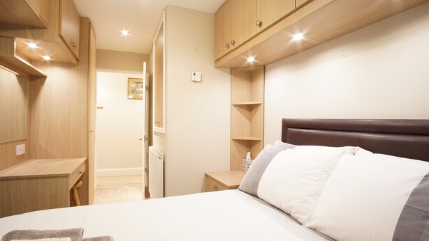 Una habitación de hotel con una cama, armarios de madera, una mesita de noche y un buró.