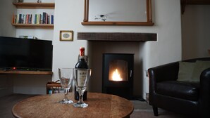 Una sala de estar con una mesa redonda de madera, una chimenea, un televisor y una estantería.