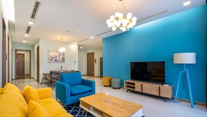 A modern living room with a blue sofa, a wooden coffee table, and a TV stand. - Stephen's Riverside Apartments (Ho Chi Minh City)