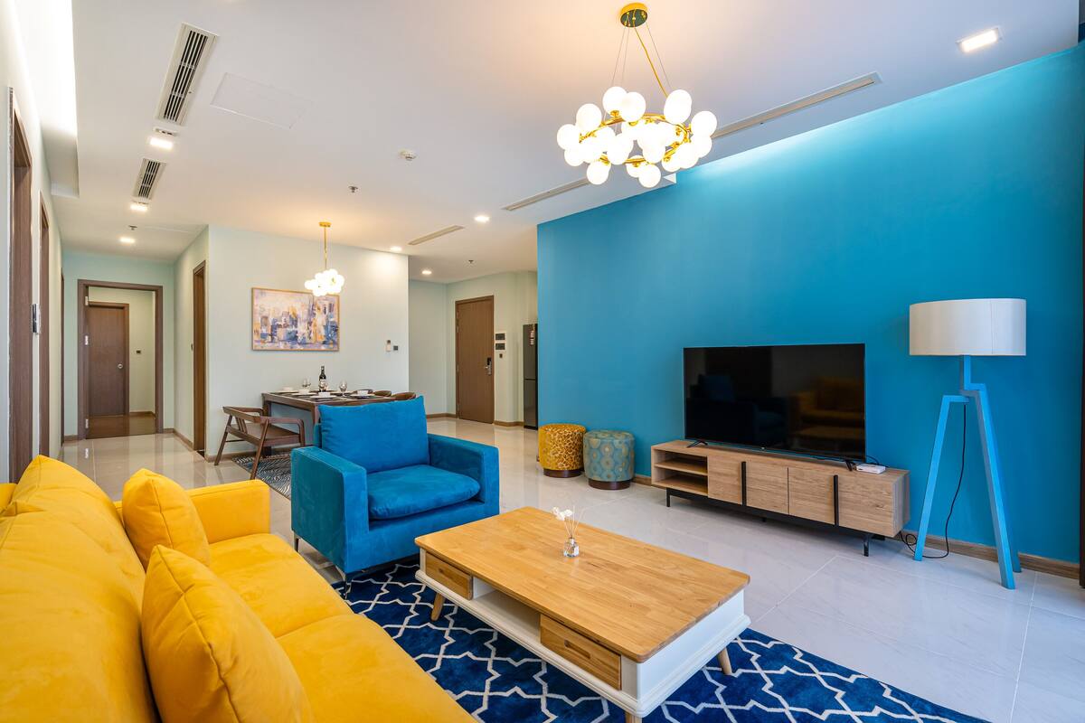 A modern living room with a blue sofa, a wooden coffee table, and a TV stand.