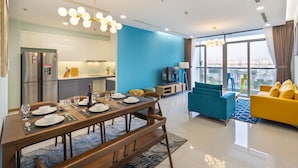 A modern living room with a dining area, a kitchen, and a large window with a city view. - Stephen's Riverside Apartments (Ho Chi Minh City)