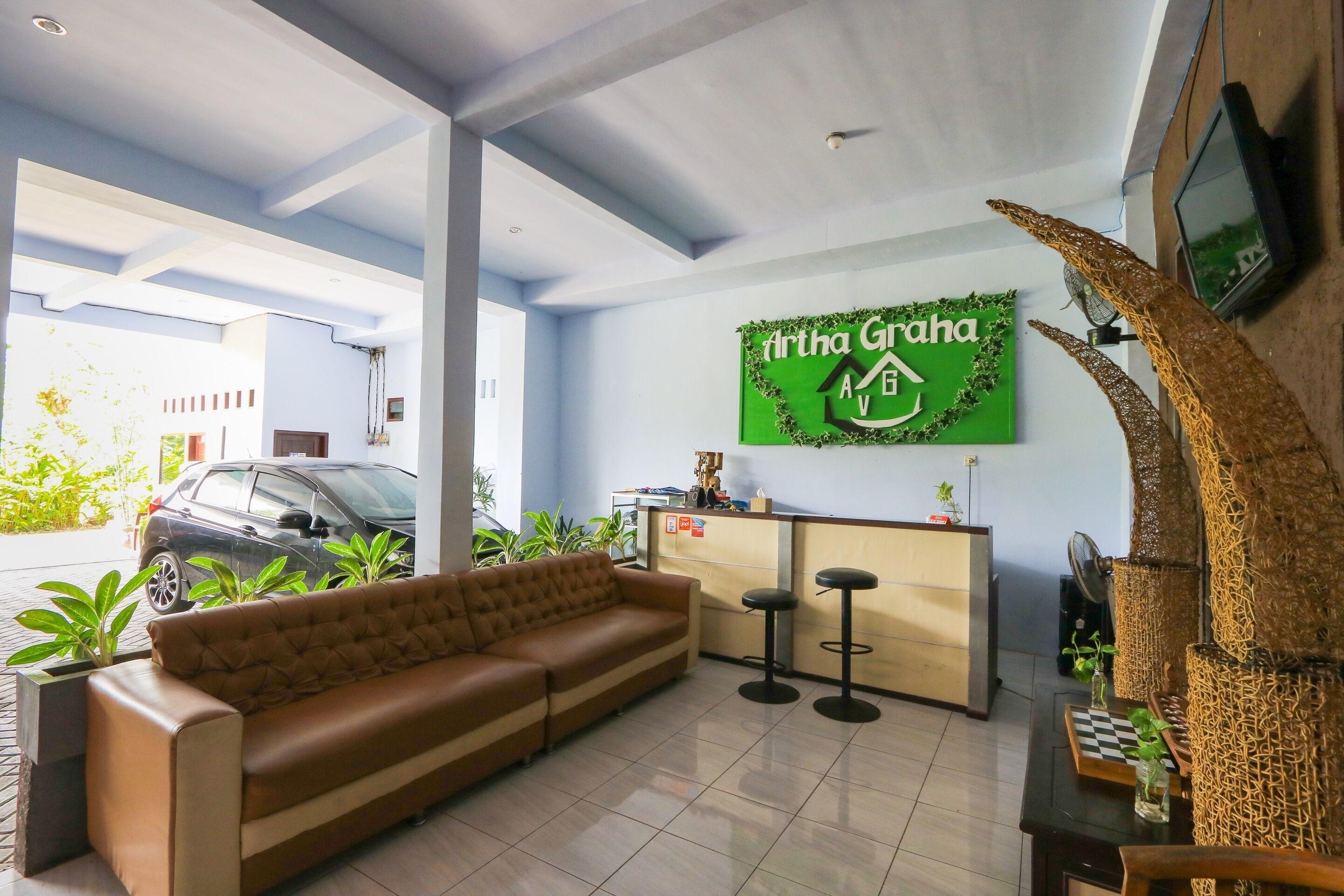 Un espace d’accueil avec un canapé, un comptoir de réception et un panneau vert.