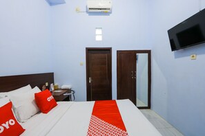 Une chambre d’hôtel avec un lit, une télévision, un climatiseur et une porte.