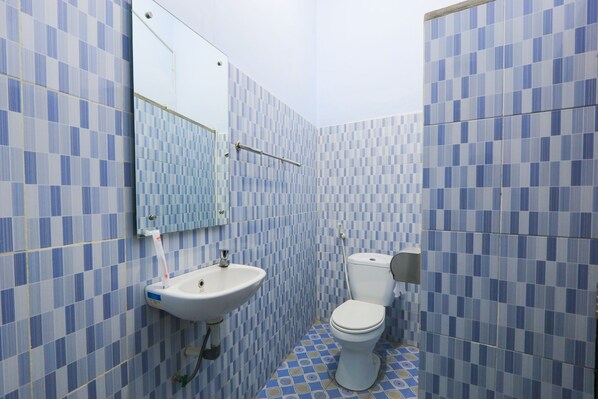 A bathroom with blue checkered tiles, a white sink, and a toilet. - OYO 2453 Artha Graha Vip (Banyuwangi)