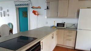 A kitchen with a granite countertop, a stove, a microwave, and a refrigerator. - Campismo Ninho 39 (Ponta d'Ouro)