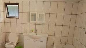 A bathroom with a toilet, sink, and bathtub. - Campismo Ninho 39 (Ponta d'Ouro)