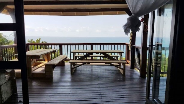 A wooden deck with a picnic table and benches, overlooking a body of water. - Campismo Ninho 39 (Ponta d'Ouro)