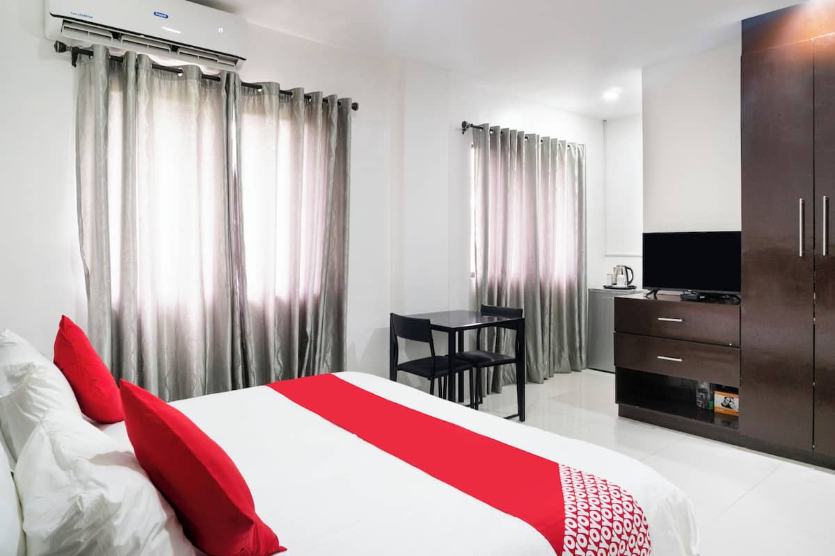 A hotel room with a bed, a desk, a TV, and a wardrobe.