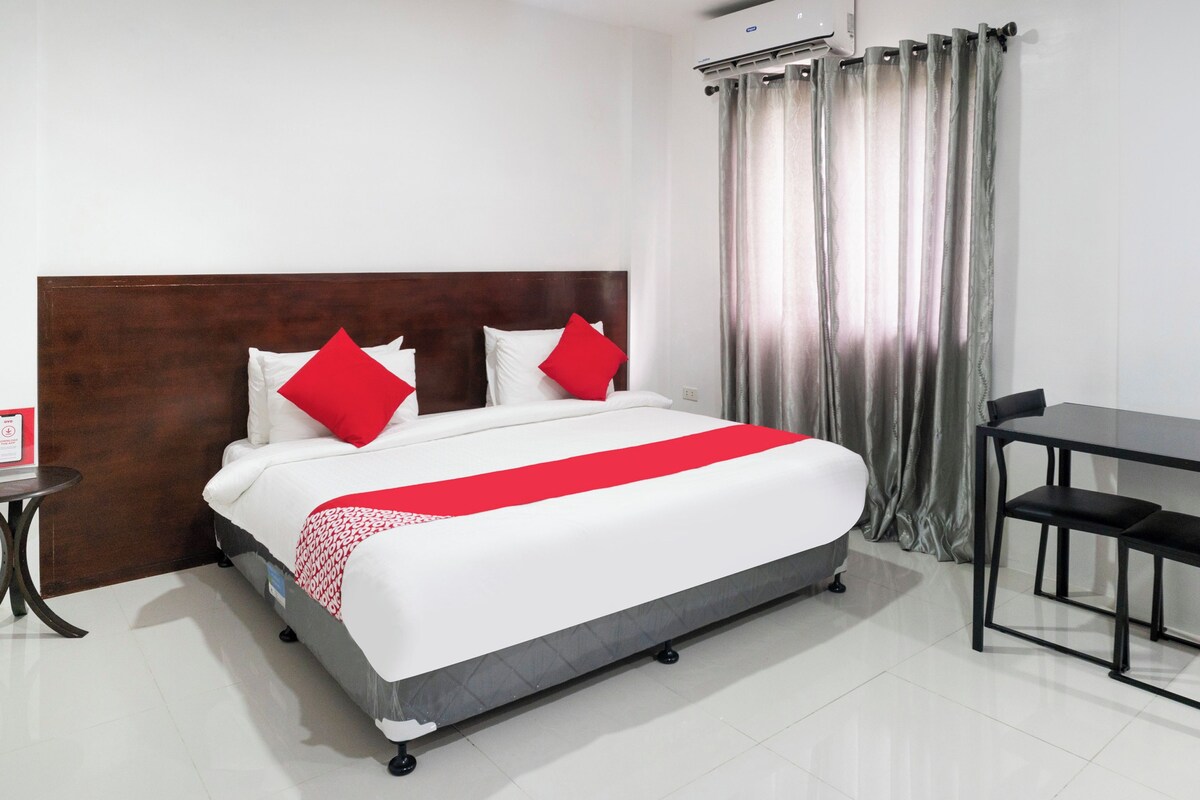 A hotel room with a bed, a desk, and a chair.