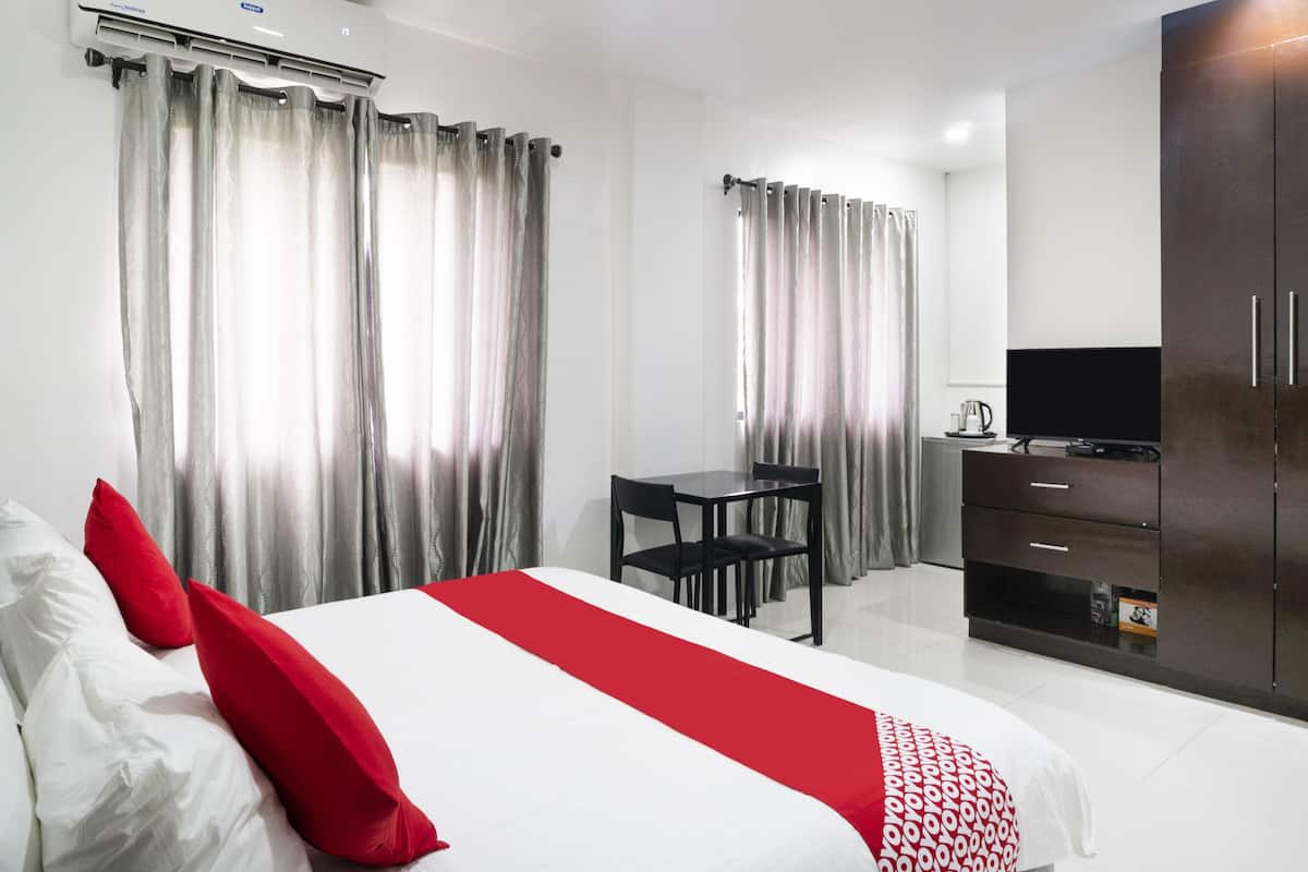 A hotel room with a bed, a desk, a TV, and a wardrobe.