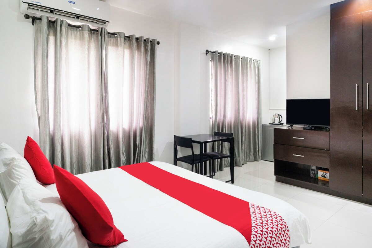A hotel room with a bed, a desk, a TV, and a wardrobe.