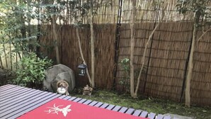 A red outdoor seating area with a bamboo fence and a small tree. - Ryu (Hatsukaichi)