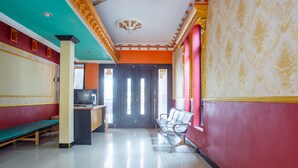 A room with a ceiling fan, a bench, a desk with a television, and a door leading to another room. - Hotel O Buana Jaya Guest House (Cilacap)