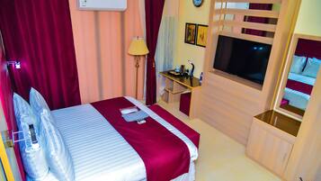 Une chambre d’hôtel équipée d’un lit, d’un bureau, d’une télévision et d’une armoire.