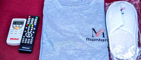 A gray t-shirt with "Montana" and a heart logo, a black and white remote control, and a white pillow in plastic packaging.