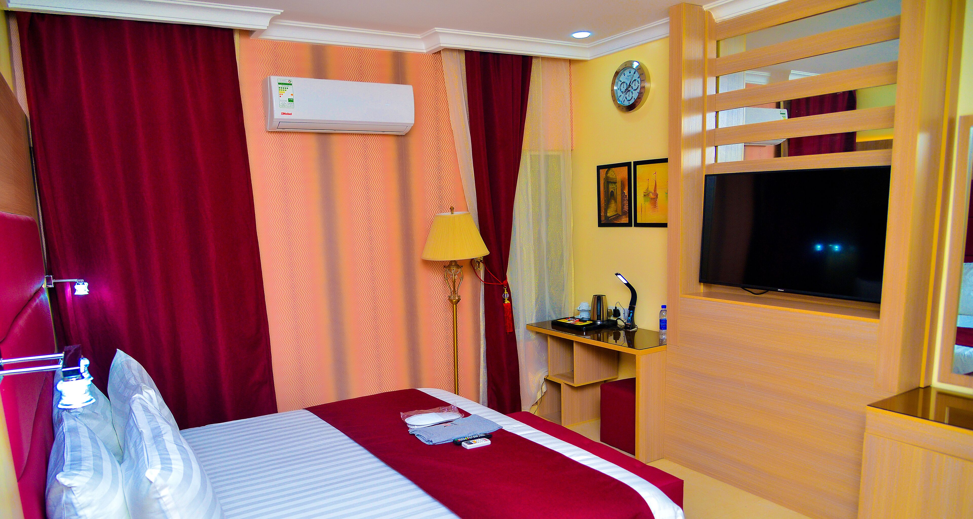 Una habitación de hotel con cama, escritorio, televisor y aire acondicionado.