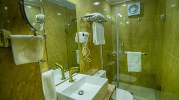 A bathroom with a sink, mirror, towel rack, and a glass-enclosed shower area.