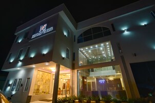 Un hotel moderno con un cartel llamativo, ventanas amplias y una entrada bien iluminada.