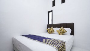 A neatly made bed with white bedding and a patterned throw. - Hotel O Berkah Residence Syariah (Gresik)