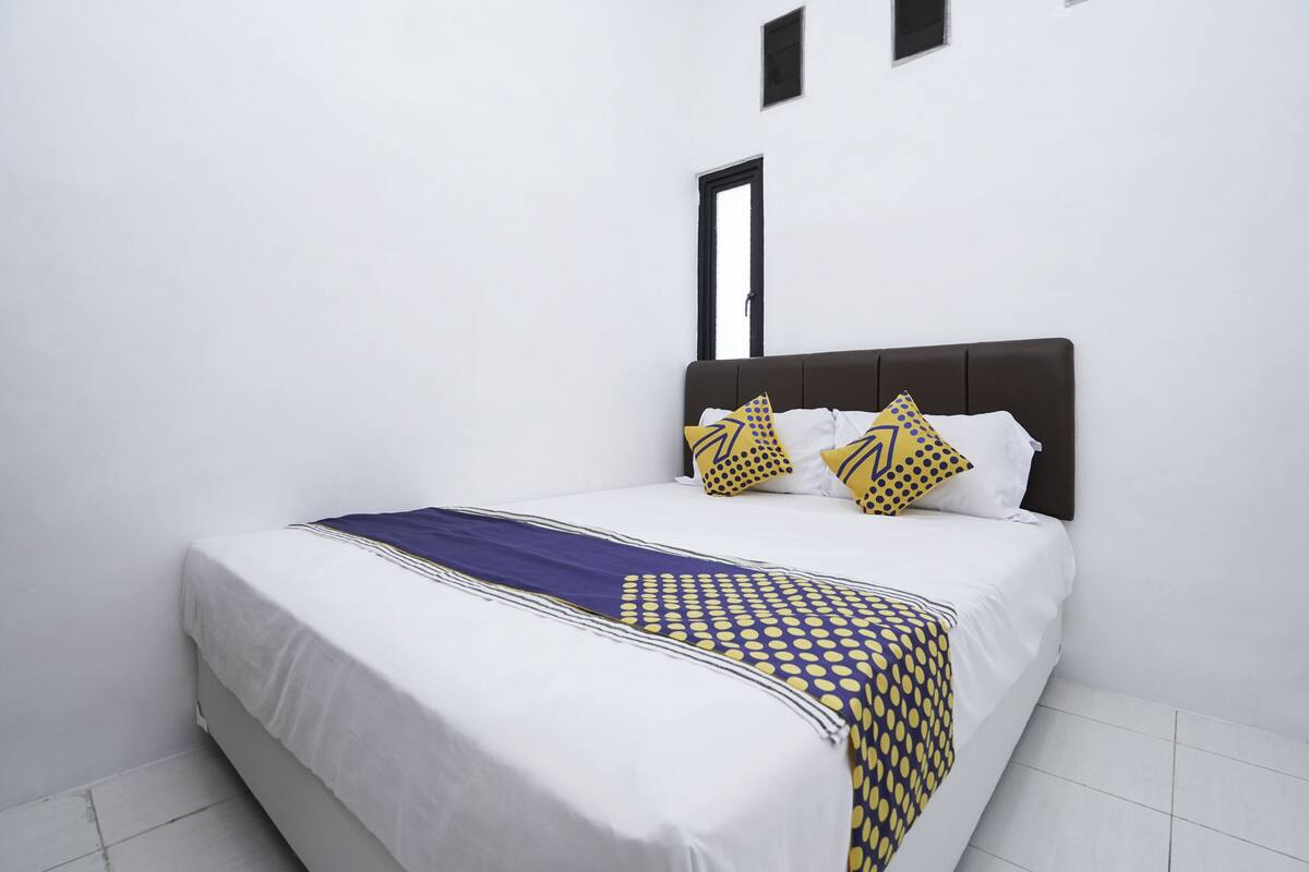 A neatly made bed with white bedding and a patterned throw.