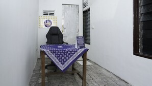A small office with a table covered by a patterned tablecloth, a chair, and a sign indicating the office is for 'SPOT ON' services. - Hotel O Berkah Residence Syariah (Gresik)