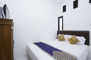 A bedroom with a bed, a wooden wardrobe, and a door.
