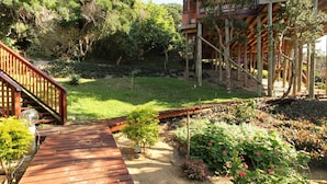 Una terraza de madera que conduce a un jardín con diversas plantas y flores.