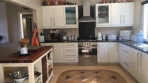 Una cocina con armarios blancos, estufa, horno y cafetera.