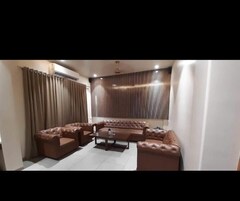 Una sala de estar con un sofá seccional de cuero marrón, una mesa de centro de vidrio y un ventilador de techo.