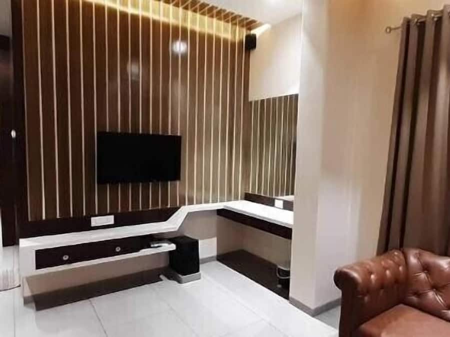Uma sala de estar moderna com uma TV de tela plana presa a uma parede de madeira, um sofá e uma janela grande com cortinas.