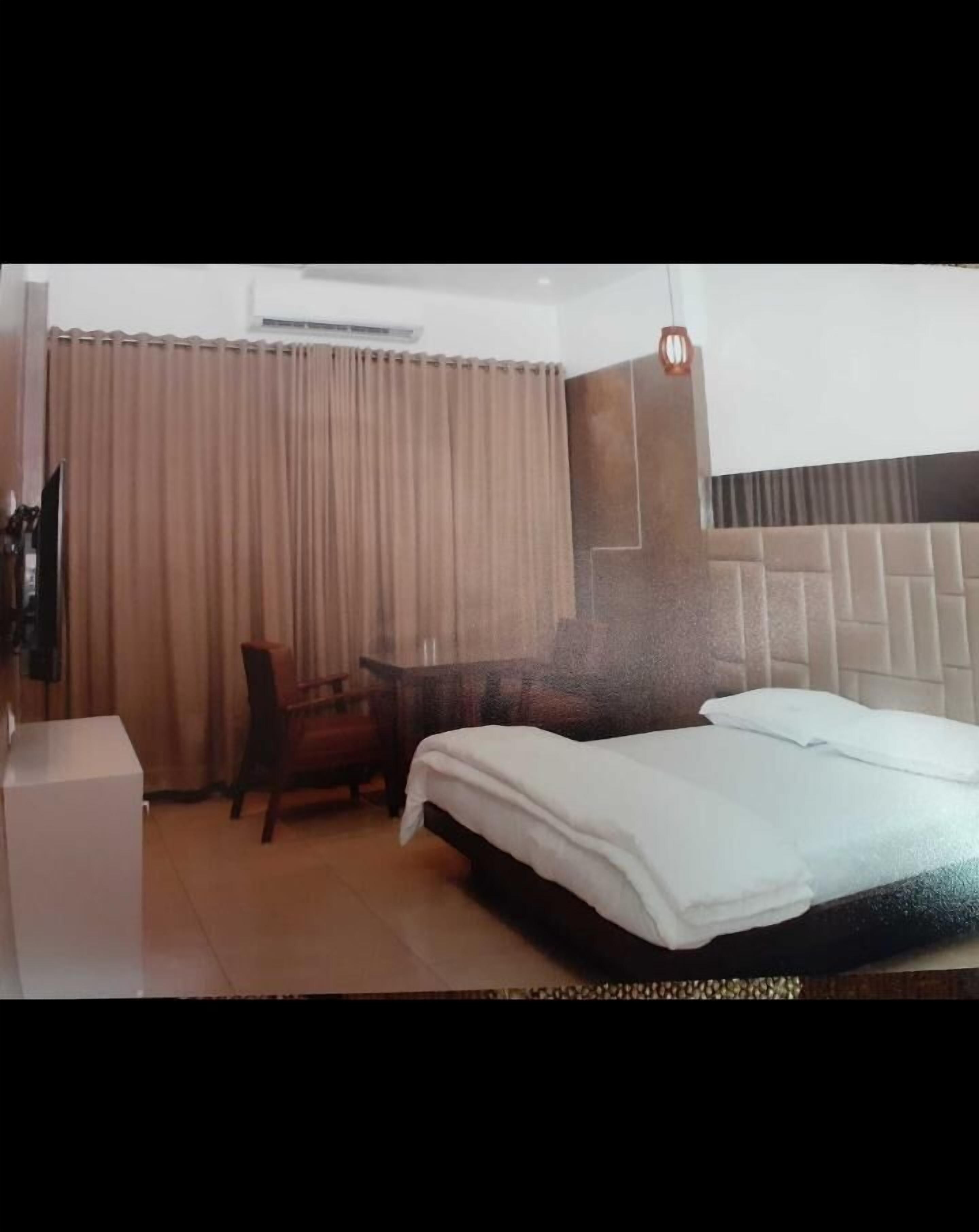 A hotel room with a bed, a desk, a chair, and a TV.