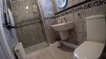 Une salle de bain avec une douche à parois de verre, un lavabo et des toilettes.