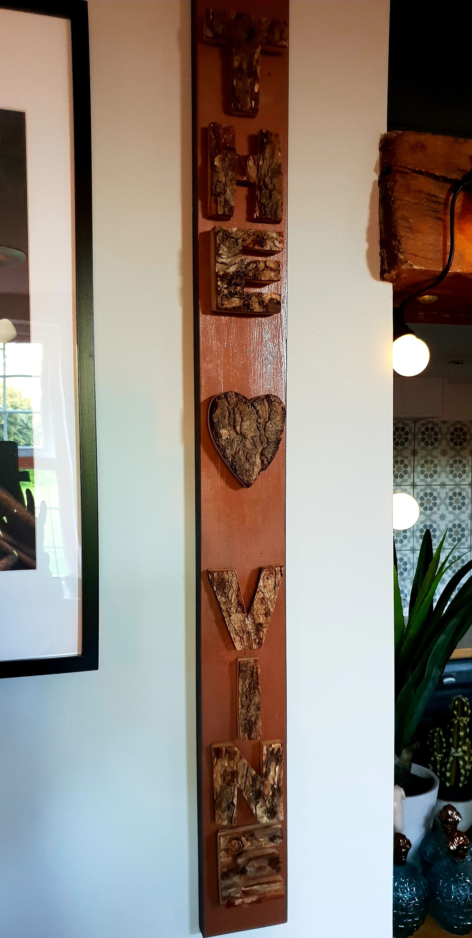 A wall with a vertical wooden sign that reads "LOVE YOU."