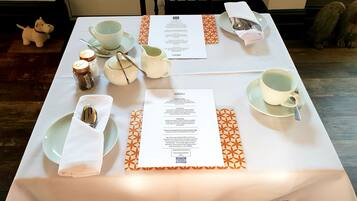 Una mesa dispuesta con un menú, tazas de té, una tetera y aderezos.