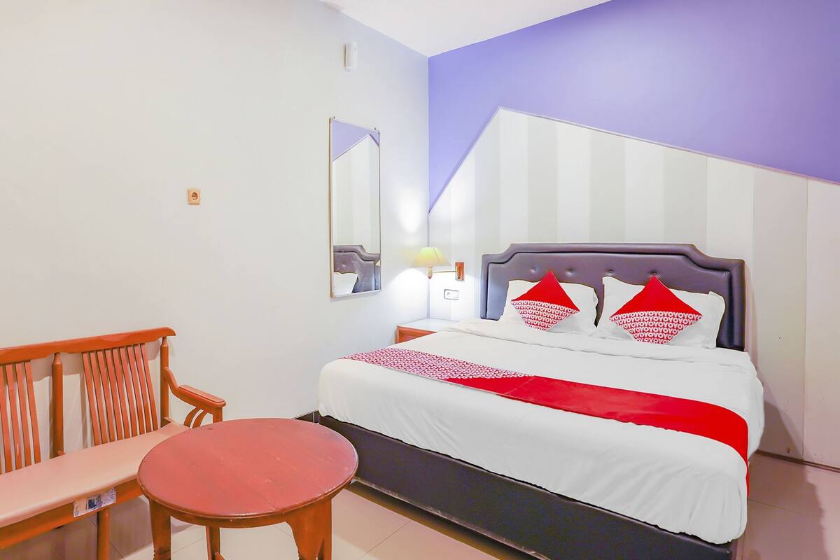 A hotel room with a bed, a bench, and a small table.