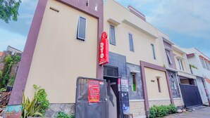 A building with a beige facade, multiple windows, and a prominent red sign. - Hotel O Gangnam Style Residence (Surabaya)