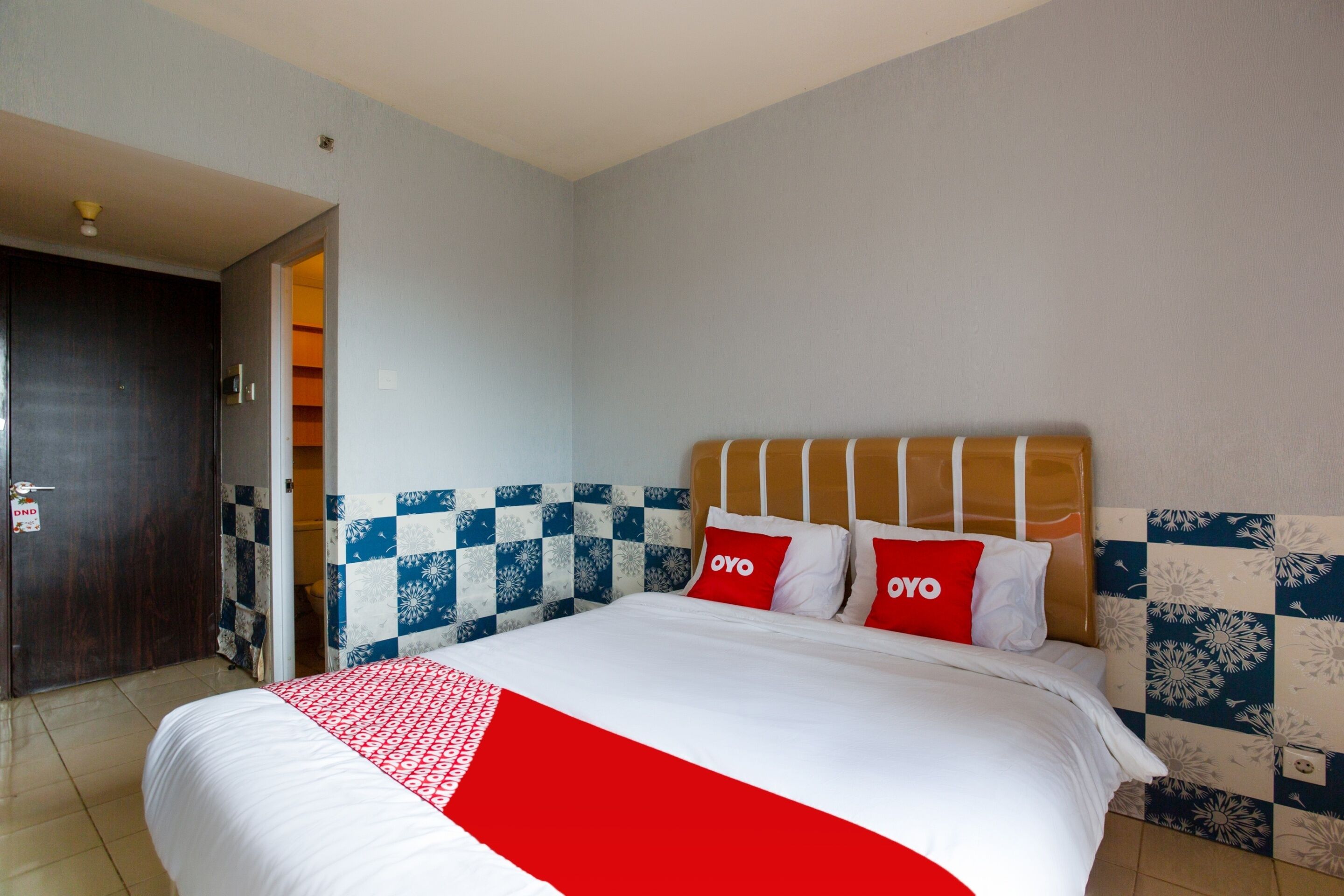 Una habitación de hotel con una cama grande, cabecera de madera y un estampado de cuadros en la pared.