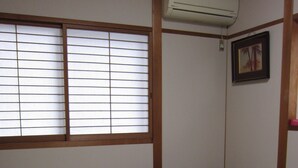 Una habitación japonesa tradicional con suelo de tatami, una mesa de madera baja y una cama futón.