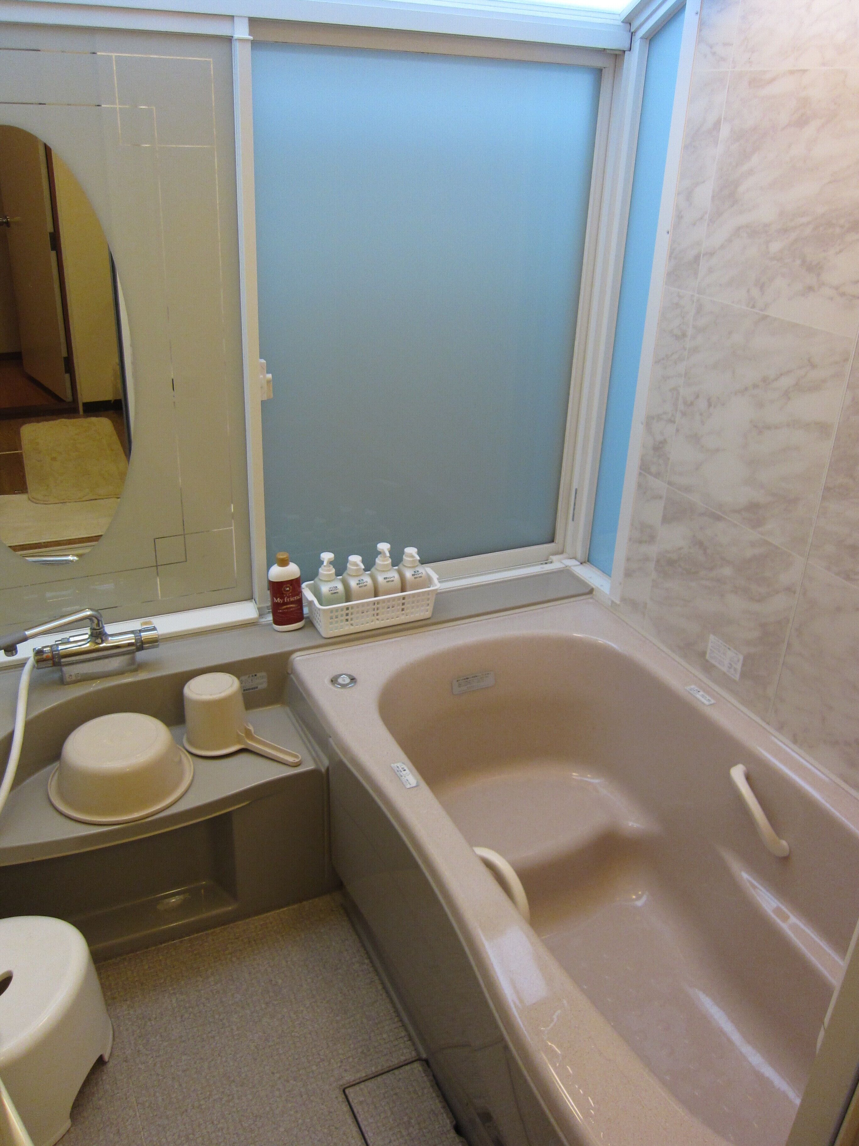 Un baño con bañera, lavabo, espejo y artículos de tocador sobre el mostrador.