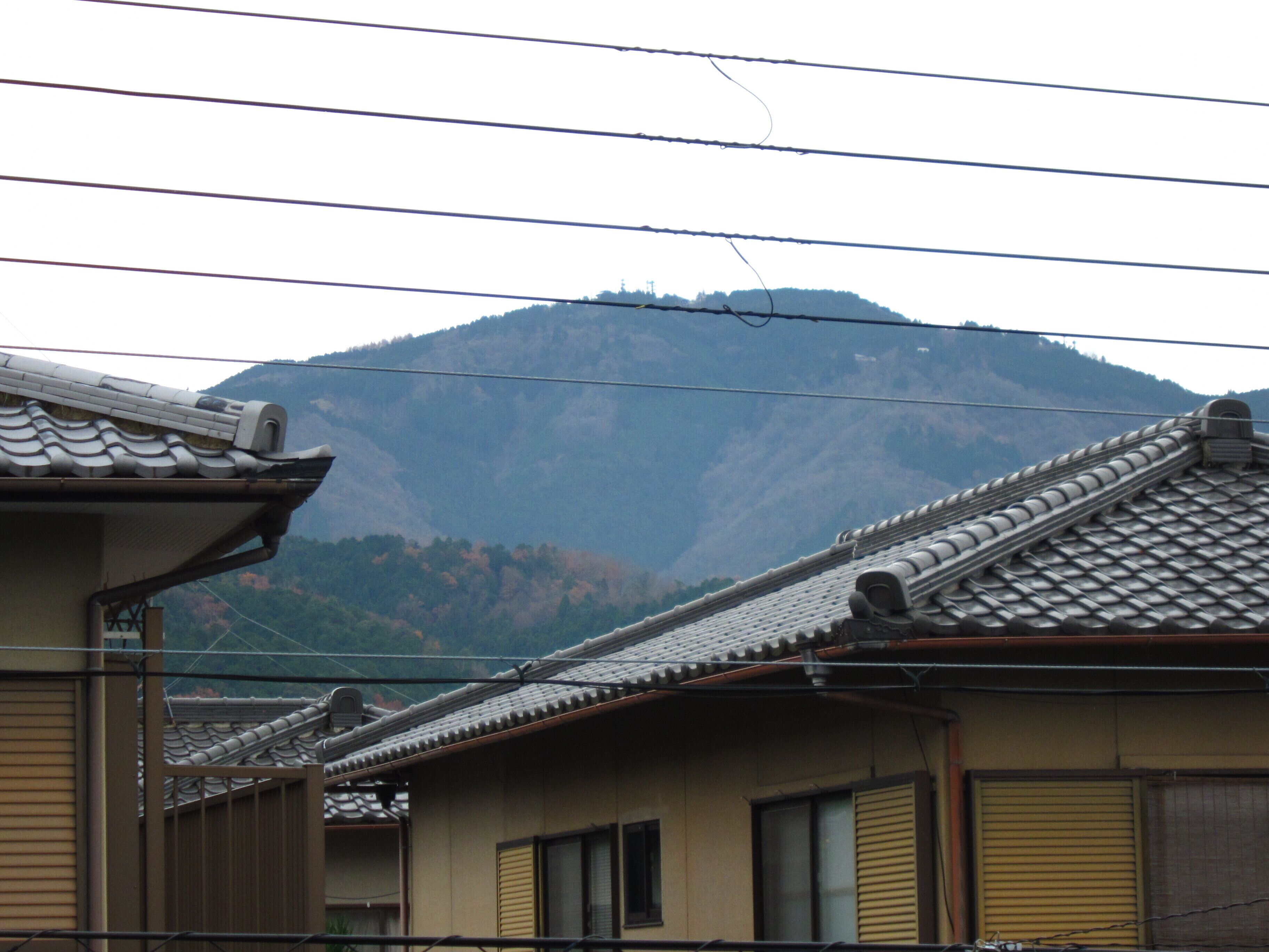 Un edificio japonés tradicional con techo de tejas, rodeado de montañas.