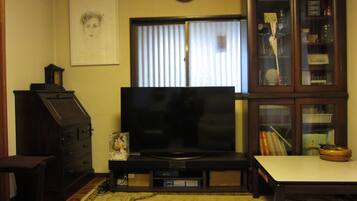 A living room with a television, a clock, a cabinet, and a framed picture on the wall.